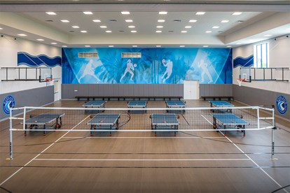 Indoor multi-sport court in GL Homes’ Port St. Lucie community, featuring a volleyball court and ping pong tables for active recreation and socializing.